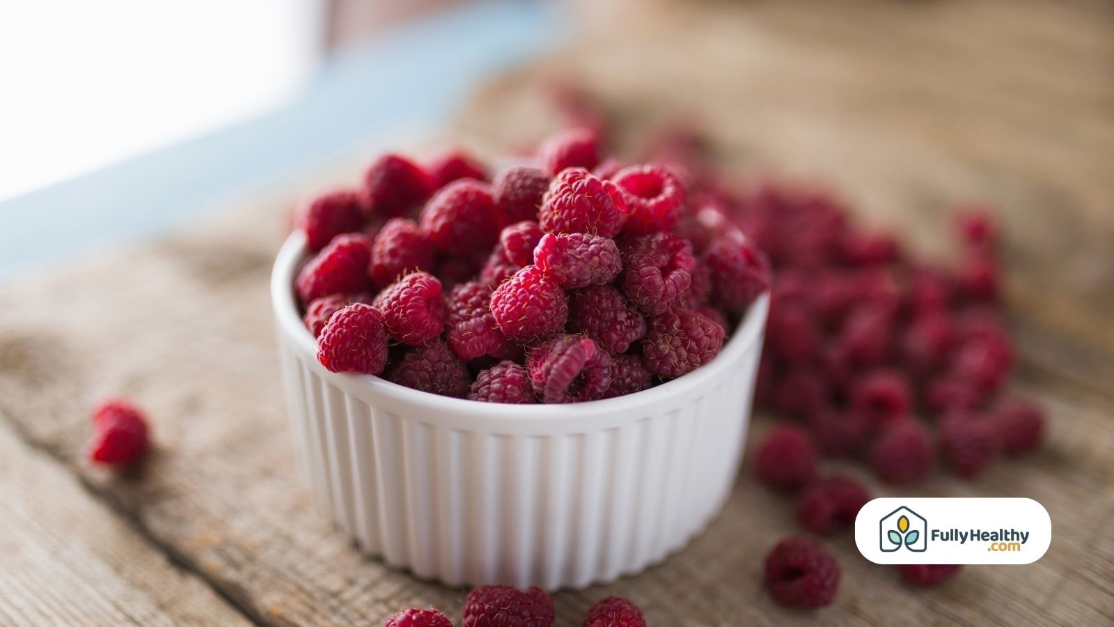 Fresh ripe raspberries in a white bowl on wooden table