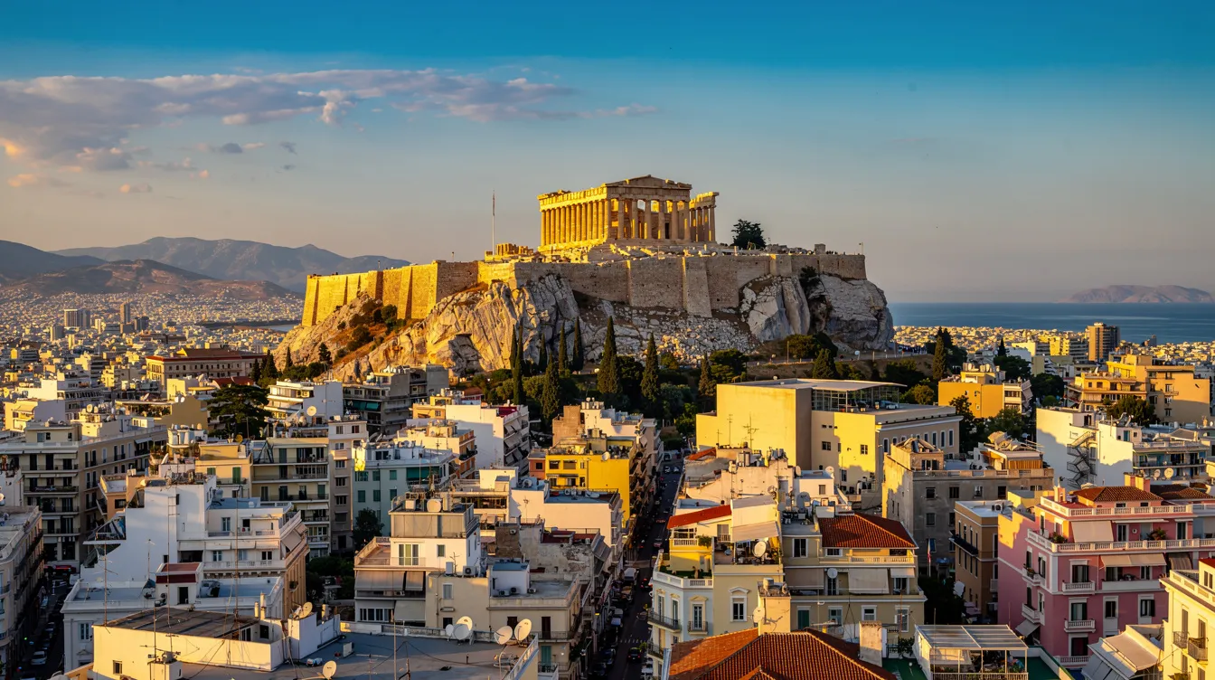 A imagem retrata a cidade de Atenas, na Grécia, destacando suas antigas ruínas e a Acropolis ao fundo, simbolizando a rica história e cultura grega. Viajantes podem explorar as ruas vibrantes e os cafés que oferecem um delicioso café da manhã, enquanto desfrutam da beleza do mar Egeu nas proximidades.