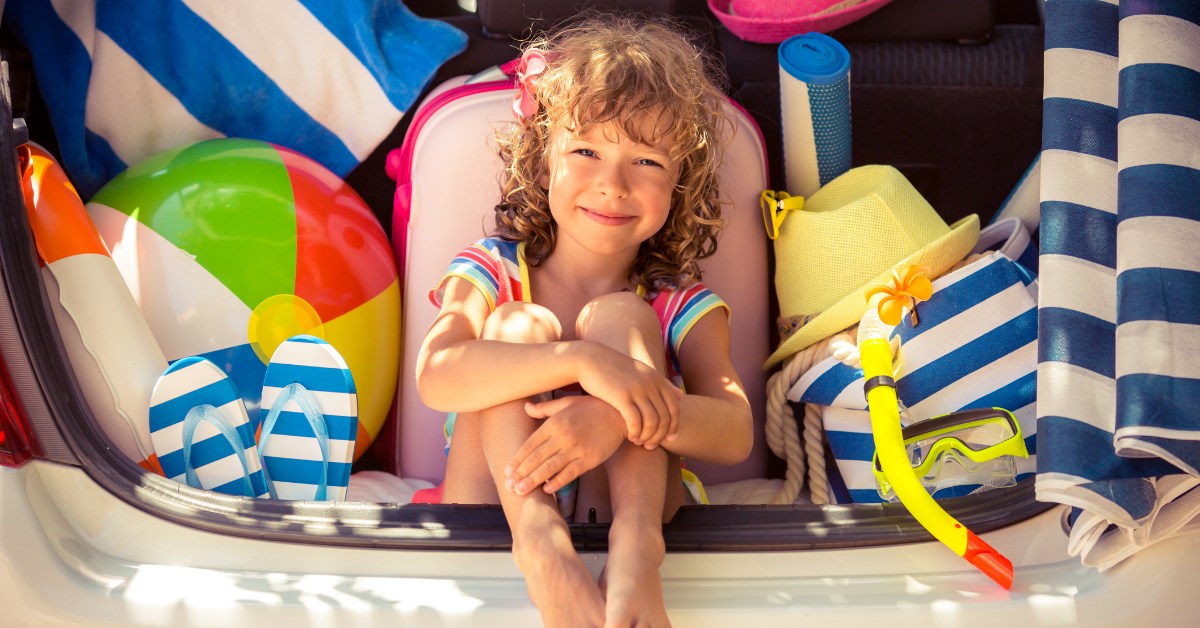 Happy child sitting in a packed car trunk with beach toys and vacation gear, ready for a family summer vacation rental in Wildwood New Jersey on the Jersey Shore