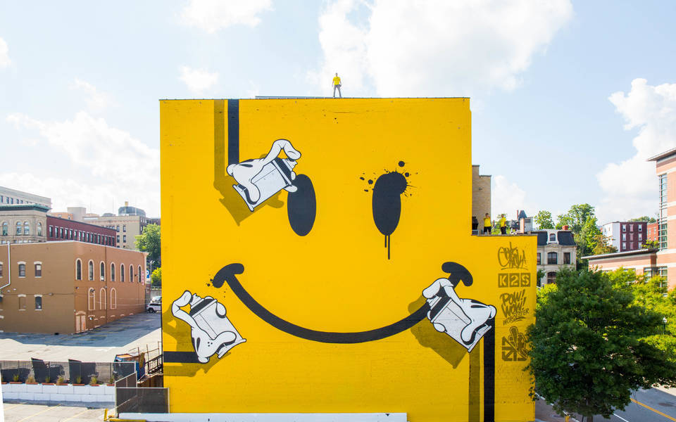Smiley Face Mural in yellow painted by POW! WOW! WOW! and OG Slick