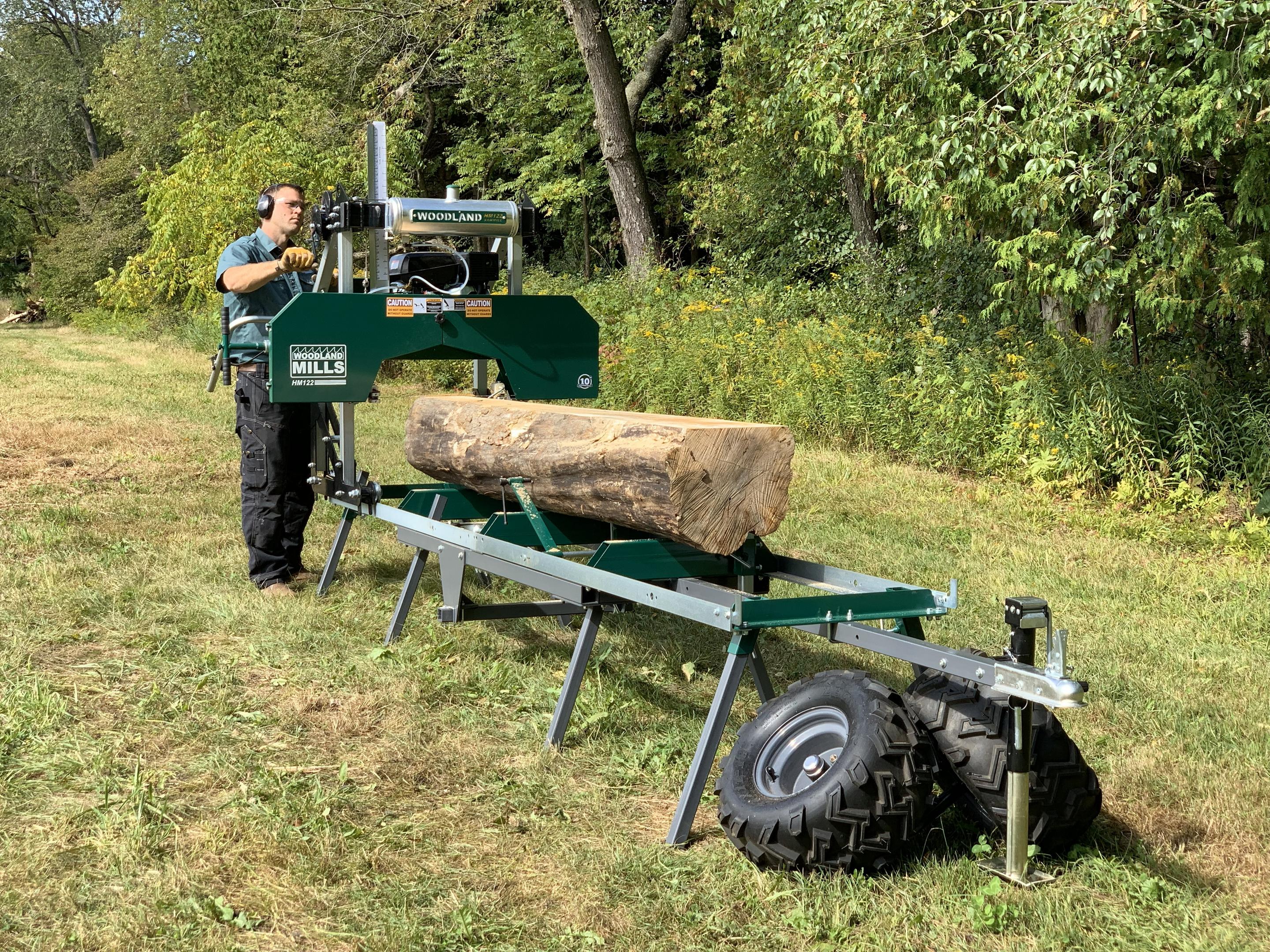 Un homme utilisant une scierie portable Woodland Mills HM122 montée sur une remorque. 