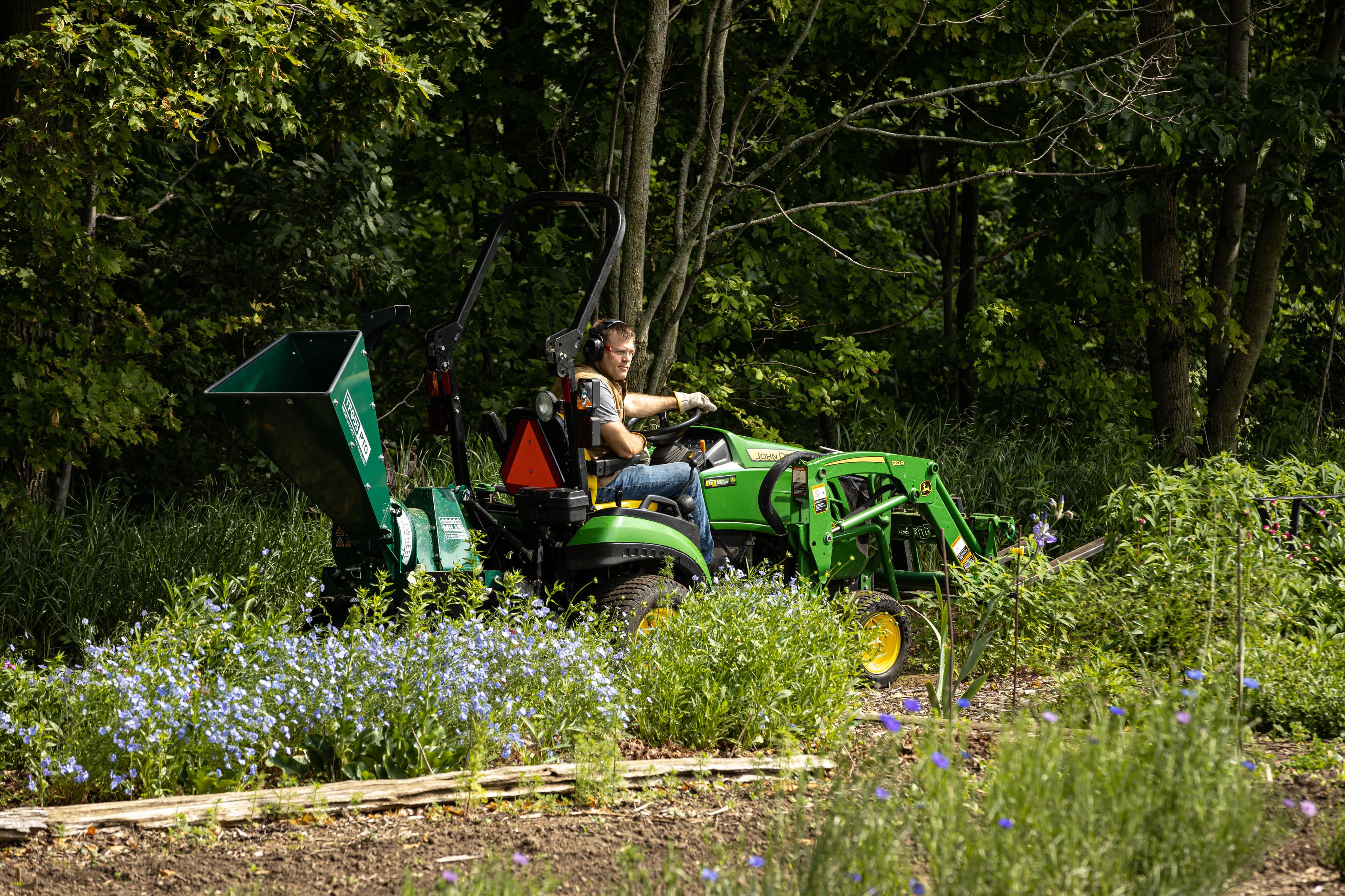 A landowner driving a tractor with a Woodland Mills TFG55 PTO Wood Chipper attached to it. 