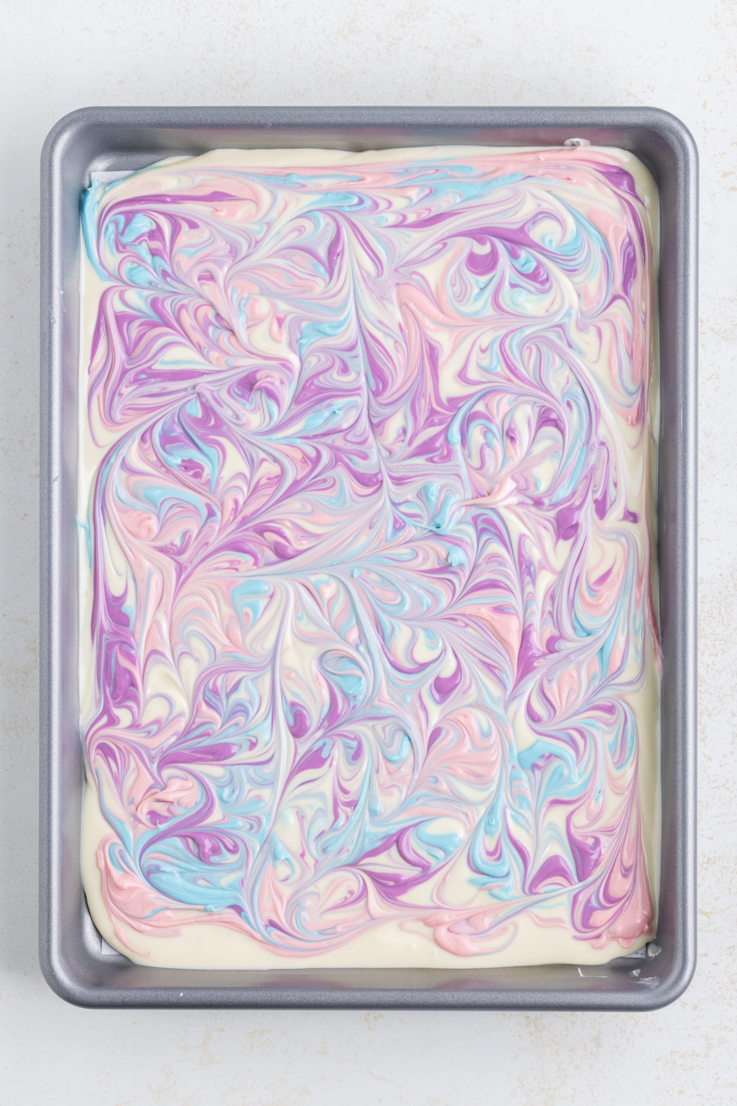 white chocolate and candy melts swirled together on baking sheet