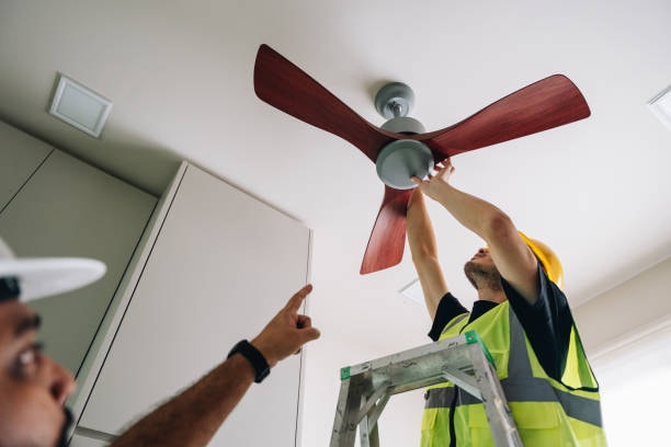 A person manually adjusting the direction switch of a ceiling fan. 