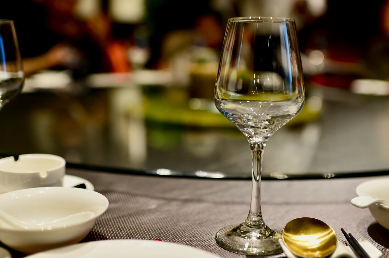 A dining table featuring a glass of wine alongside a bowl of food, highlighting proper table etiquette.
