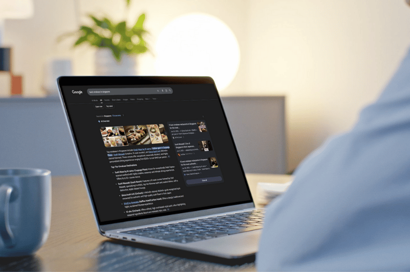 A person viewing a Google search result page on a laptop in a dimly lit room. The screen shows an AI-generated overview for "best omakase in Singapore," highlighting how AI Overviews (SGE) are dominating search results in 2026.
