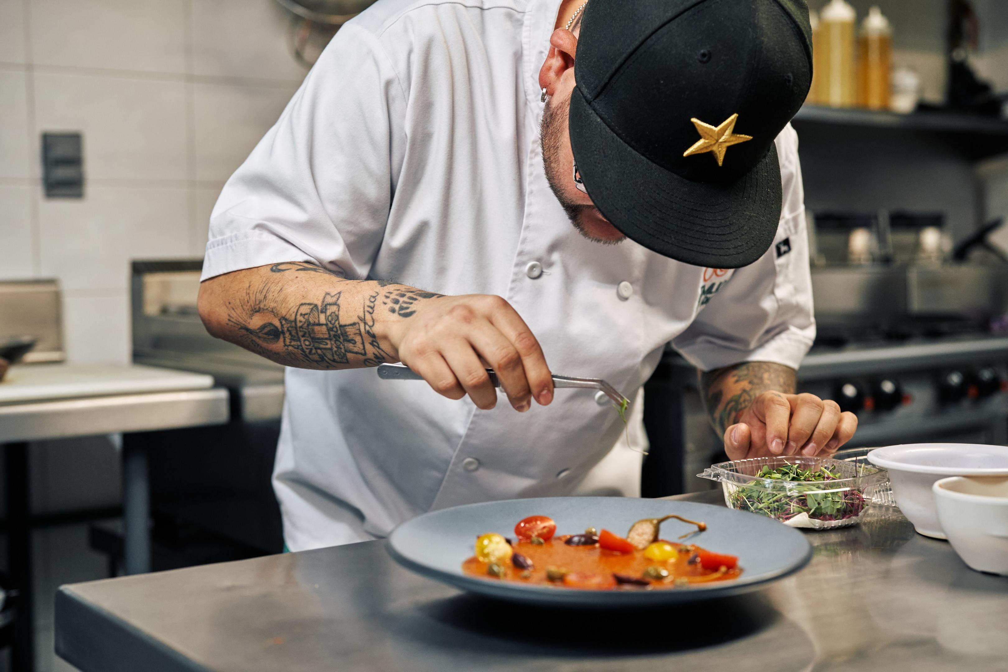 A restaurant owner is seen reviewing a checklist in a clean and well-organized commercial kitchen, ensuring adherence to food safety standards and efficient kitchen management. The environment reflects effective restaurant kitchen management practices, with clearly defined areas for food prep and kitchen operations.