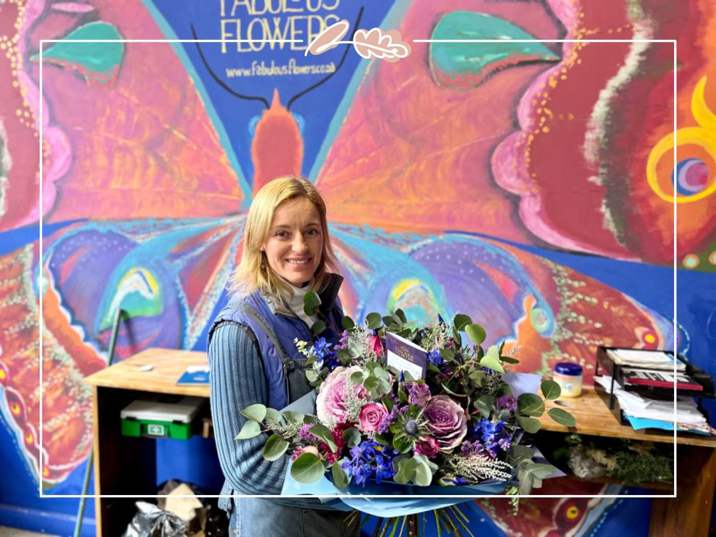 Woman smiling while displaying a blue and purple flower arrangement by Fabulous Flowers and Gifts