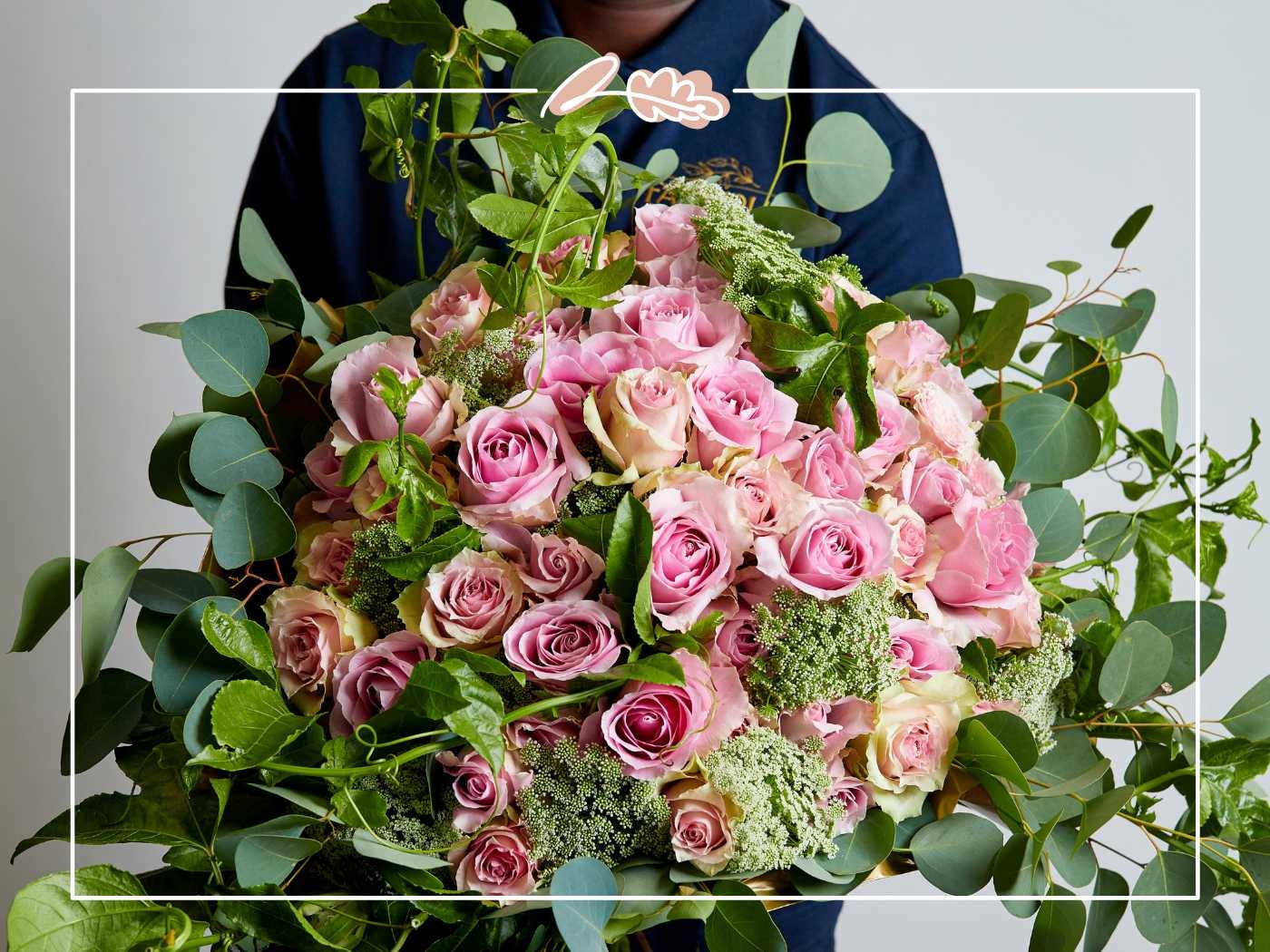 Person holding a large bouquet of pink roses and greenery by Fabulous Flowers and Gifts