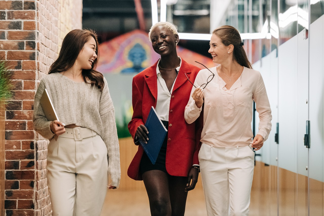 Three female coworkers networking while walking through the office