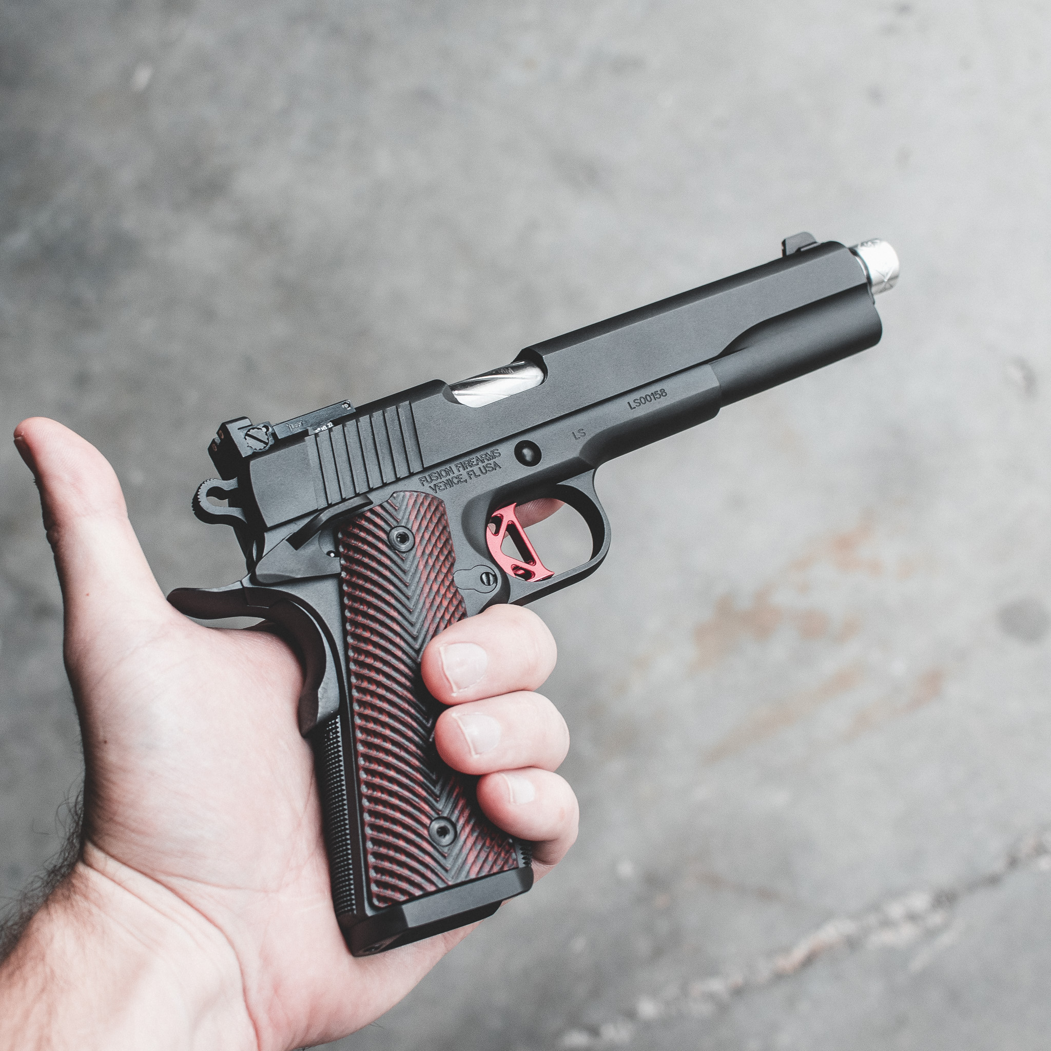 A custom 1911 pistol with a threaded barrel and suppressor attachment