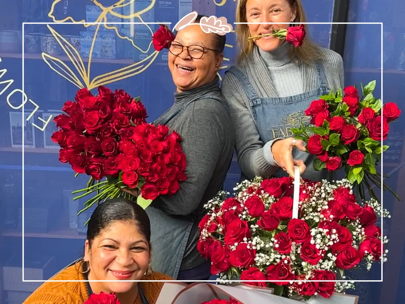 Three smiling florists holding large bouquets of red roses, with one florist playfully holding a rose in her mouth - Fabulous Flowers and Gifts