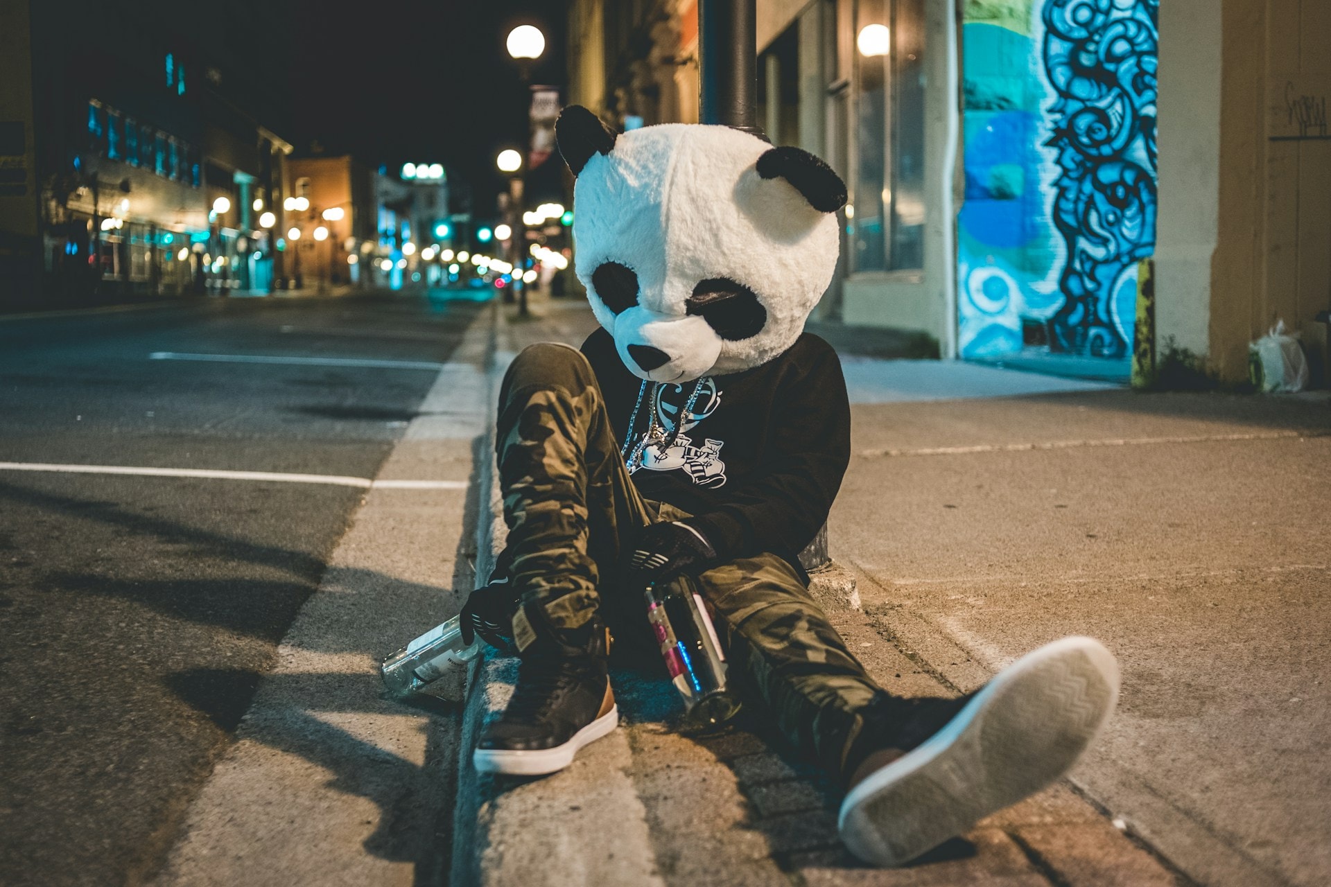 A man passed out in the street surrounded by two empty bottles wearing a panda mask - https://unsplash.com/photos/man-wearing-panda-costume-leaning-on-post-OUxM_P9JFBw