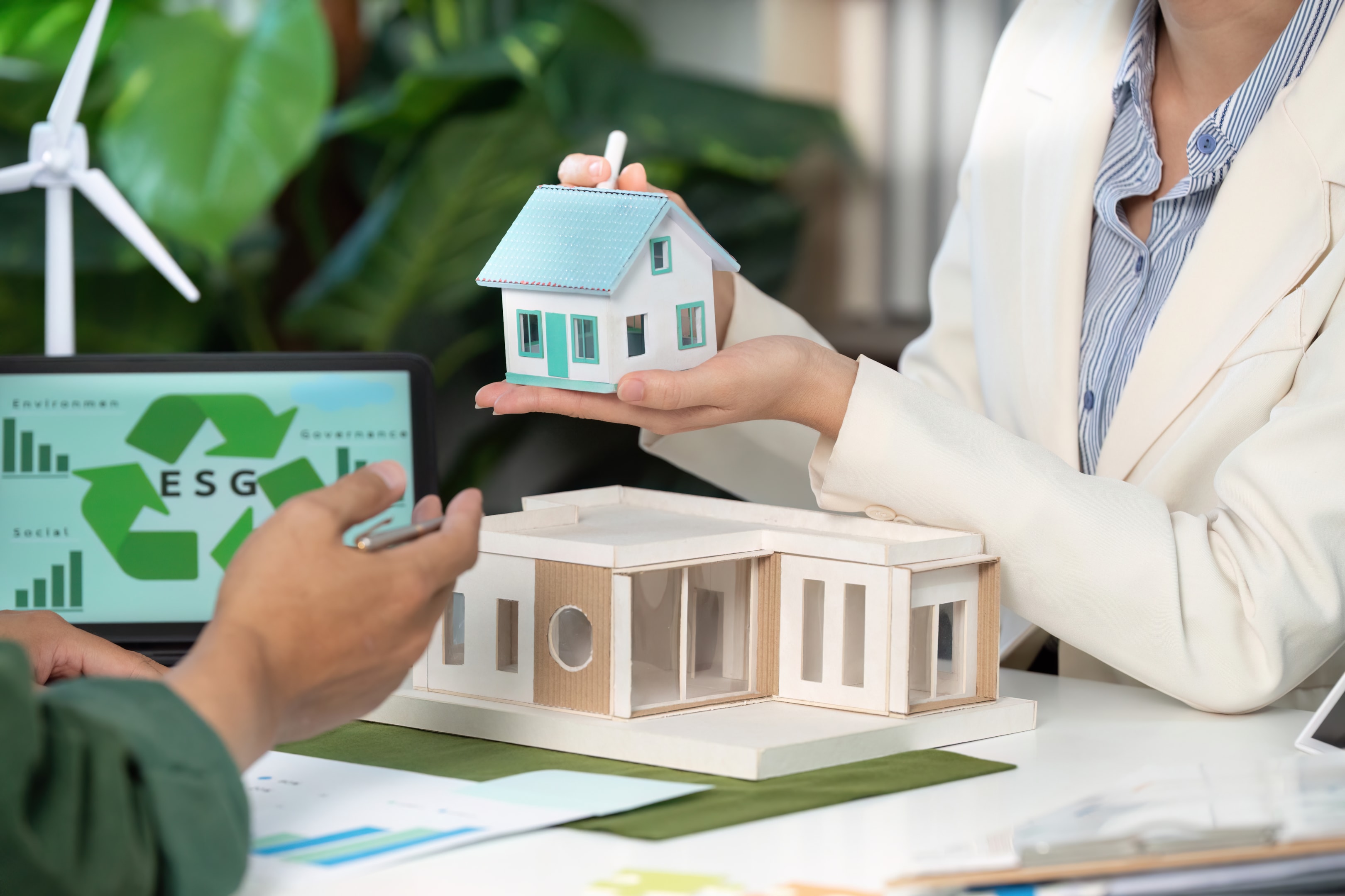 Professionals showcasing sustainable housing models in a collaborative meeting.