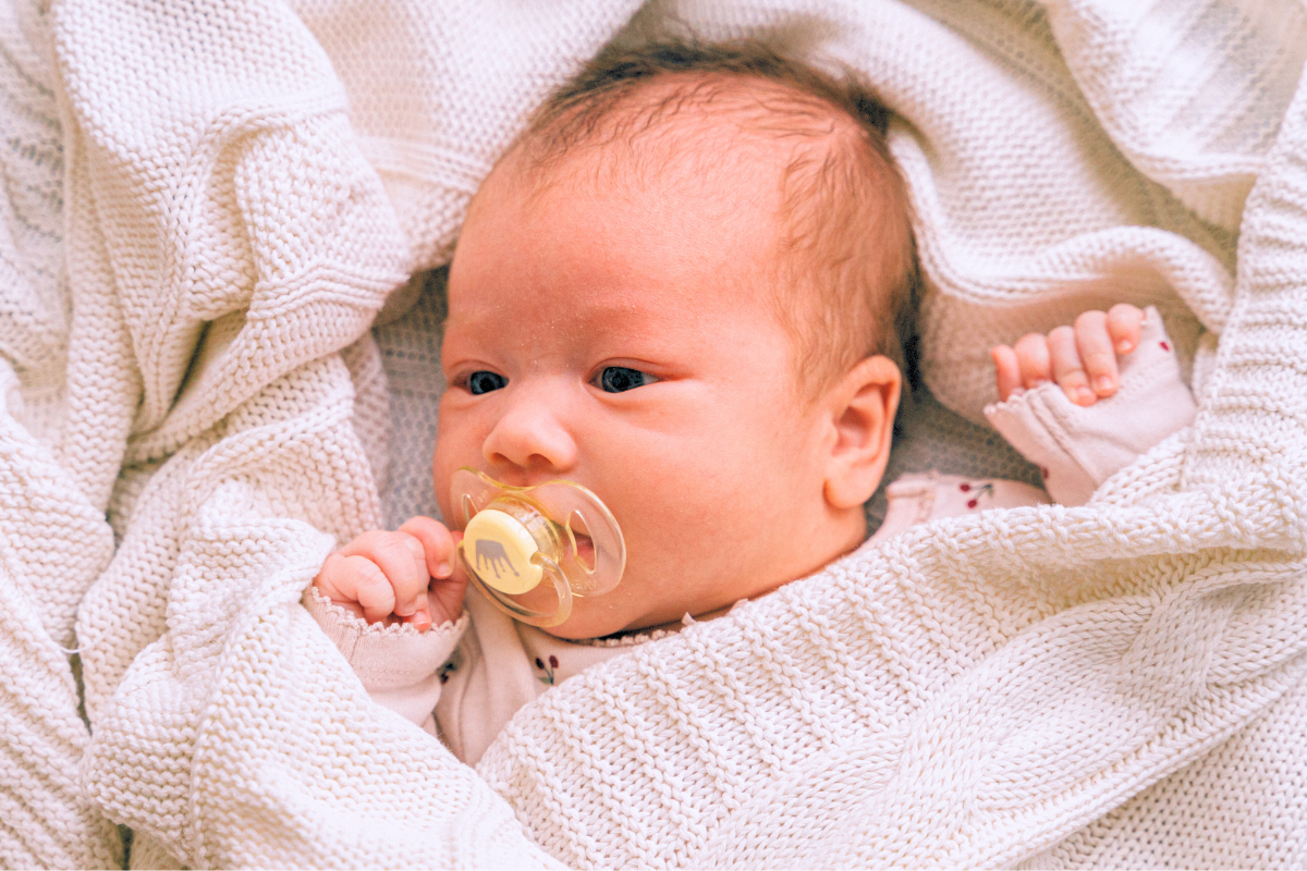 Newborn with binkie and pacifier in mouth