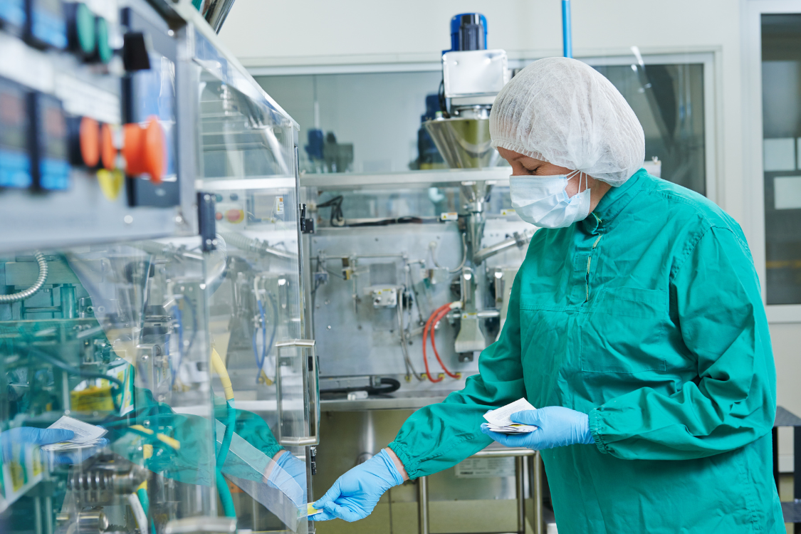 Technician in a cleanroom inspecting equipment in a certified supplement manufacturing facility