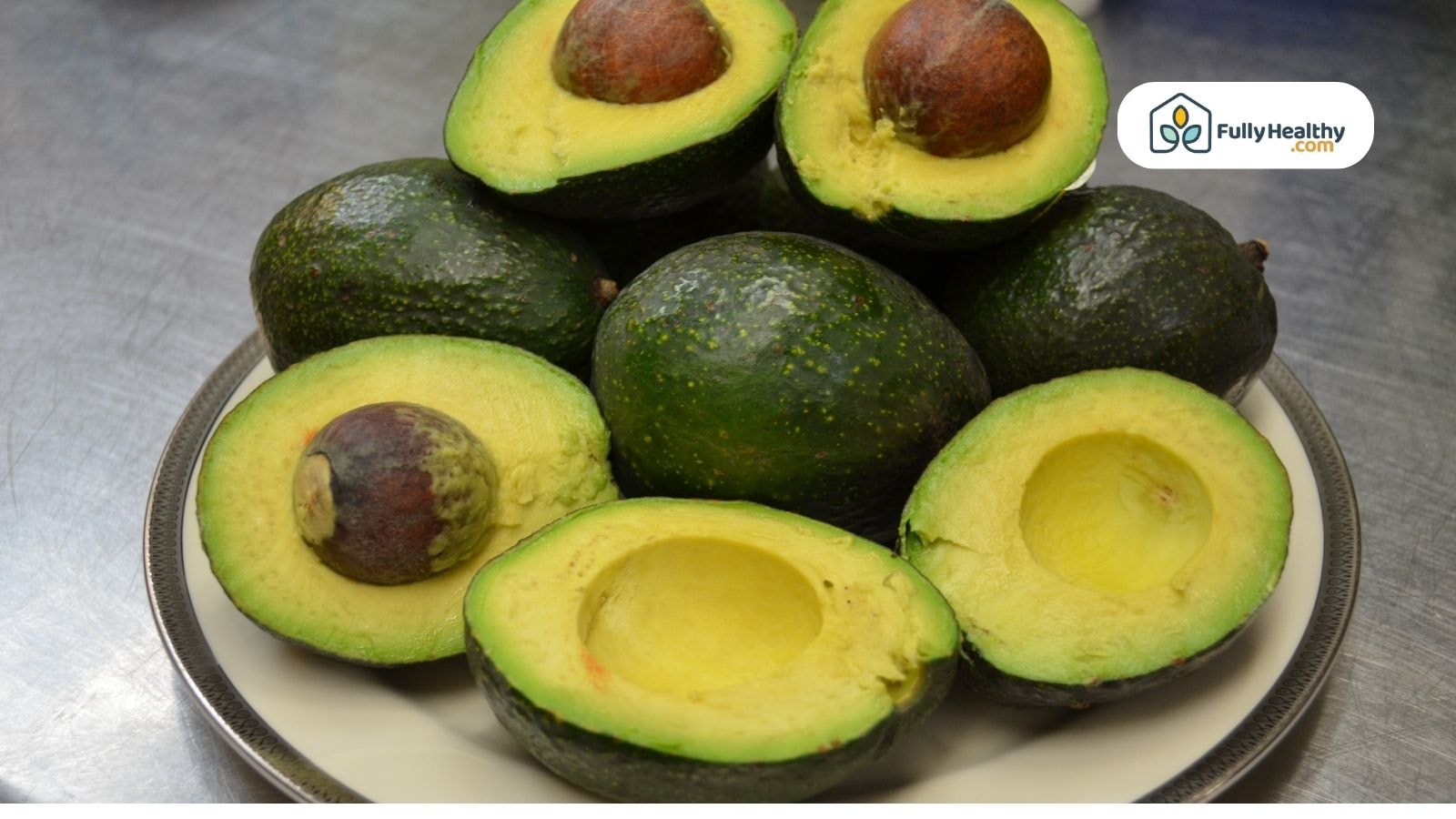 Ripe avocados sliced open on a plate with pits visible