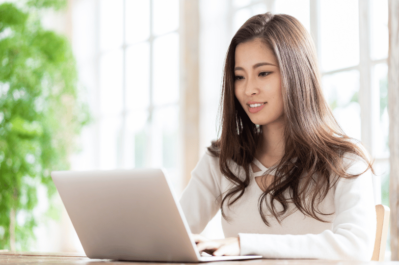 A smiling woman working on a laptop in a bright office, representing a successful restaurant marketer optimizing for AI search queries.