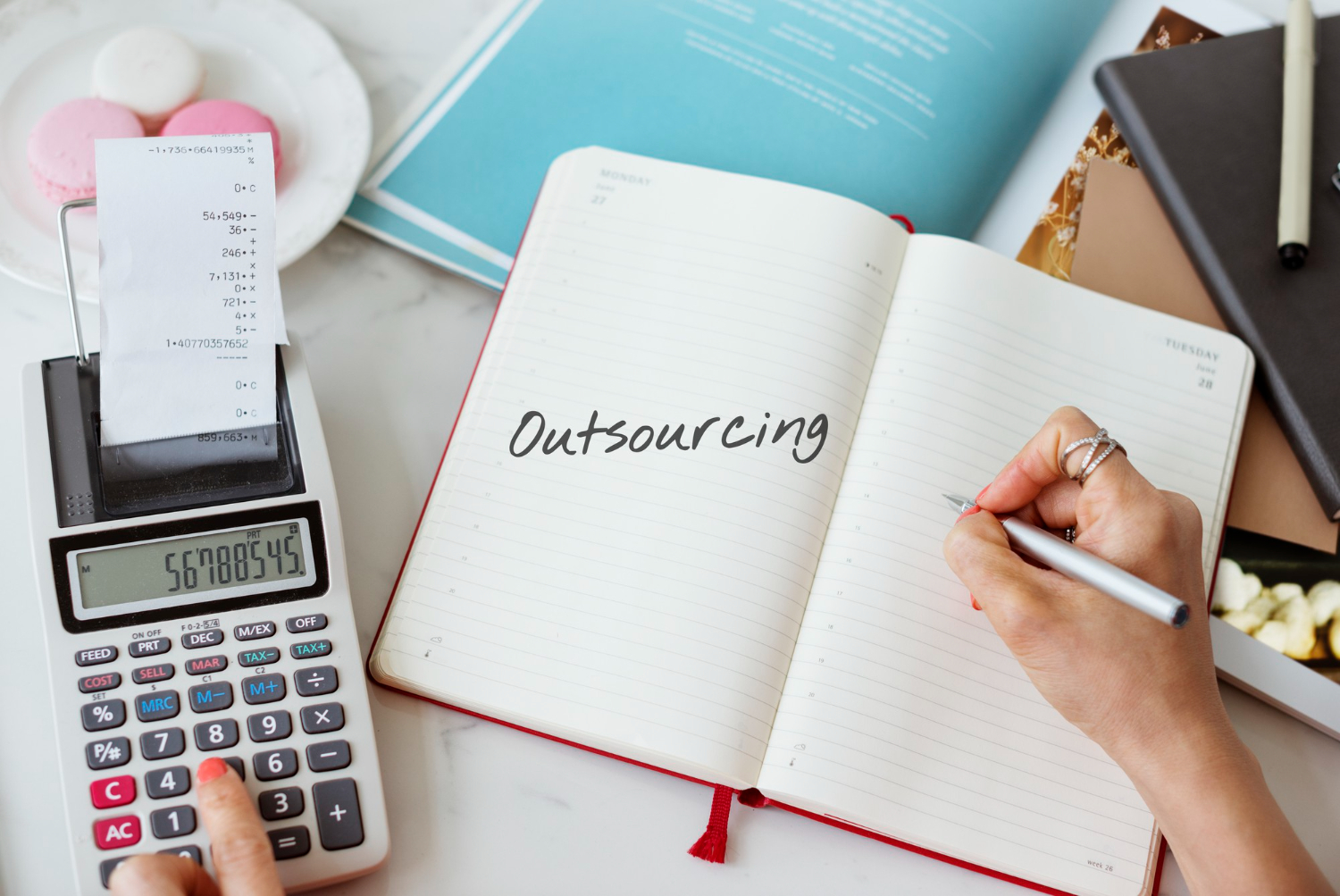 A person writing outsourcing and calculating the cost