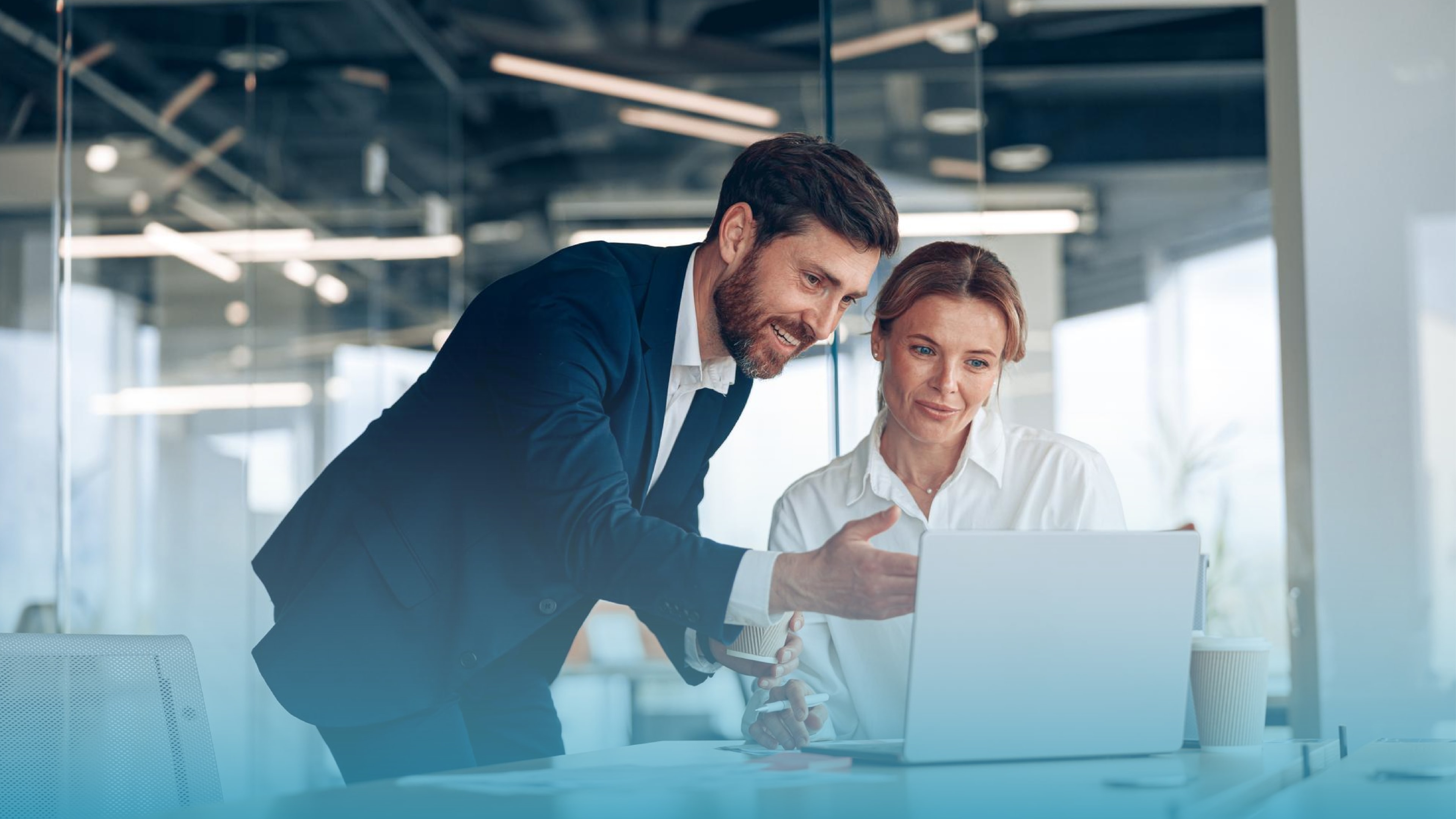 Man in a suit pointing at a laptop screen beside a woman, illustrating business internet plans used as a primary connection for business customers.