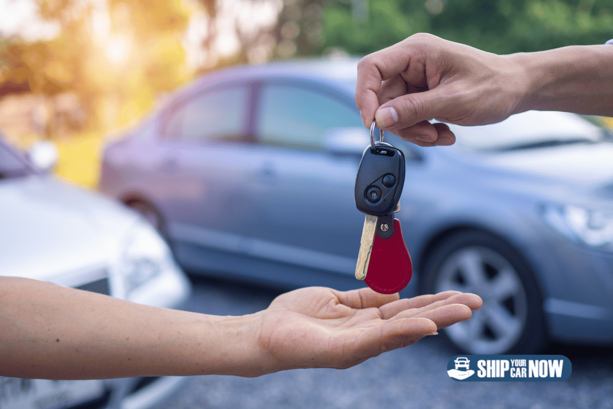 Man giving woman set of car keys with car in the background