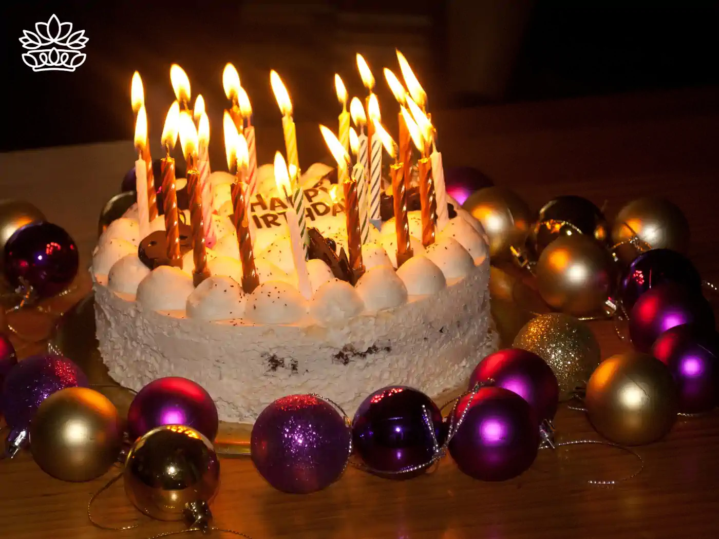 A birthday cake with candles lit, surrounded by festive decorations - Fabulous Flowers and Gifts.