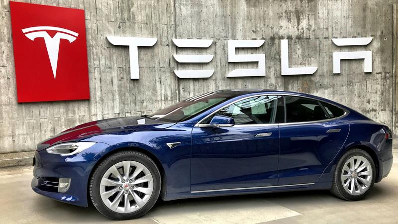 Tesla Model S infront of Tesla sign