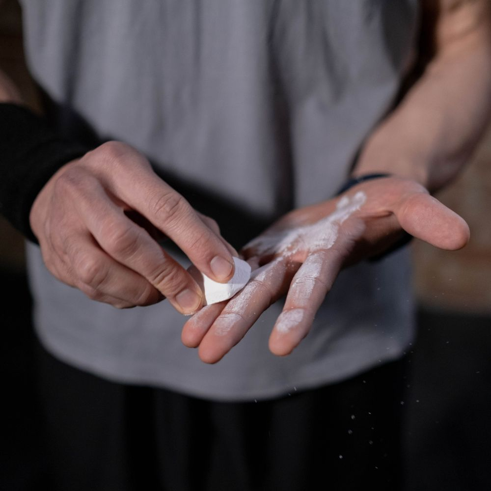 A person applying gym chalk to their hands