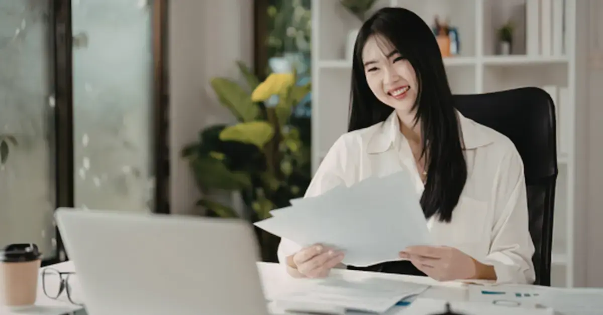 A woman focused on how to pay less in taxes, reviewing her tax documents on a laptop at her desk.