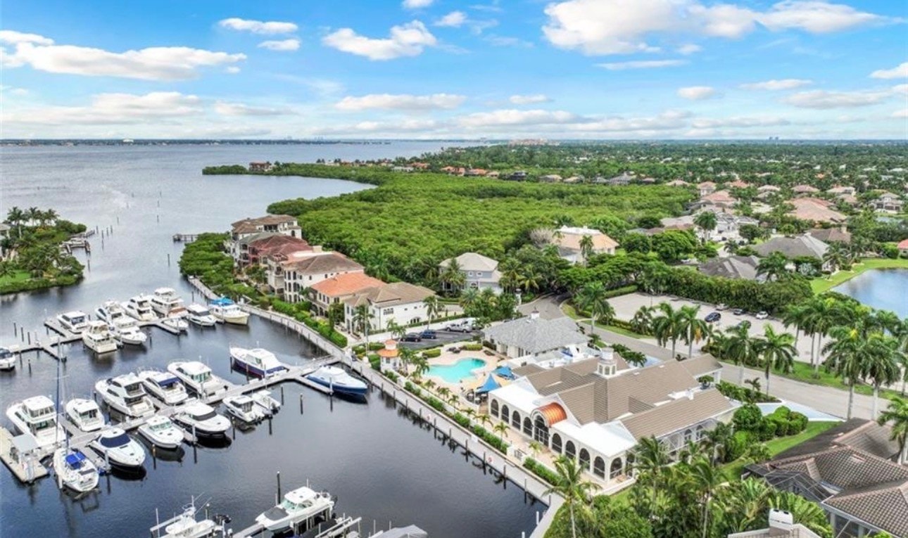 The image depicts an elegant yacht club dining room in Fort Myers, featuring upscale interior design and stunning waterfront views of the Caloosahatchee River. The ambiance is perfect for social events, with direct access to the beautifully secluded natural harbor and accommodating yachts.