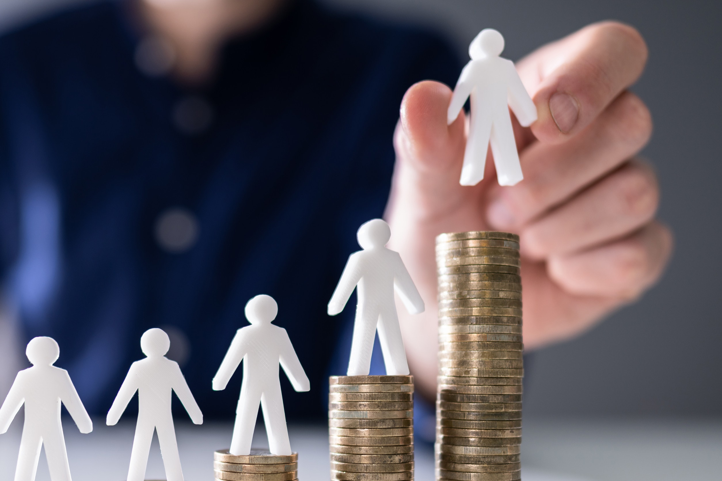 A pile of money representing out of pocket expenses with paper figurines sitting on top