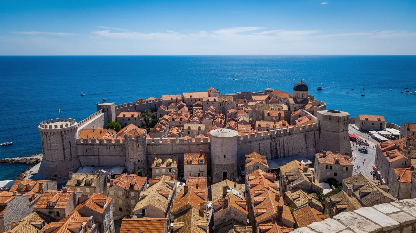 Vista panorâmica da cidade antiga de Dubrovnik, na Croácia, com suas impressionantes muralhas medievais e o azul intenso do Mar Adriático ao fundo, em um dia ensolarado. A imagem destaca a beleza histórica e a rica cultura da região, atraindo turistas de todo o mundo.