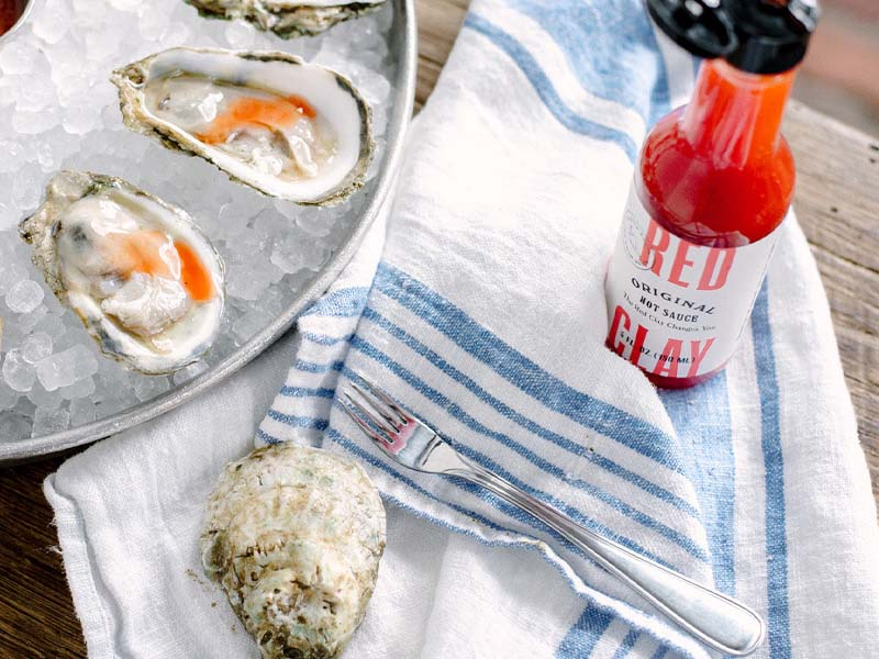 Image showing Red Clay Hot Sauce with freshly shucked oysters.