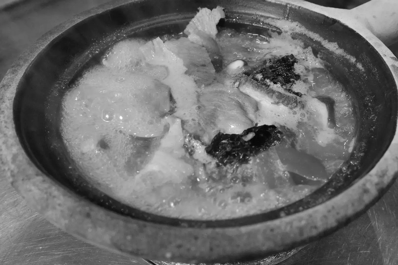 A bowl of Grandpa’s Pomfret Soup filled with tender pomfret pieces, vegetables, and a bubbling clear broth.