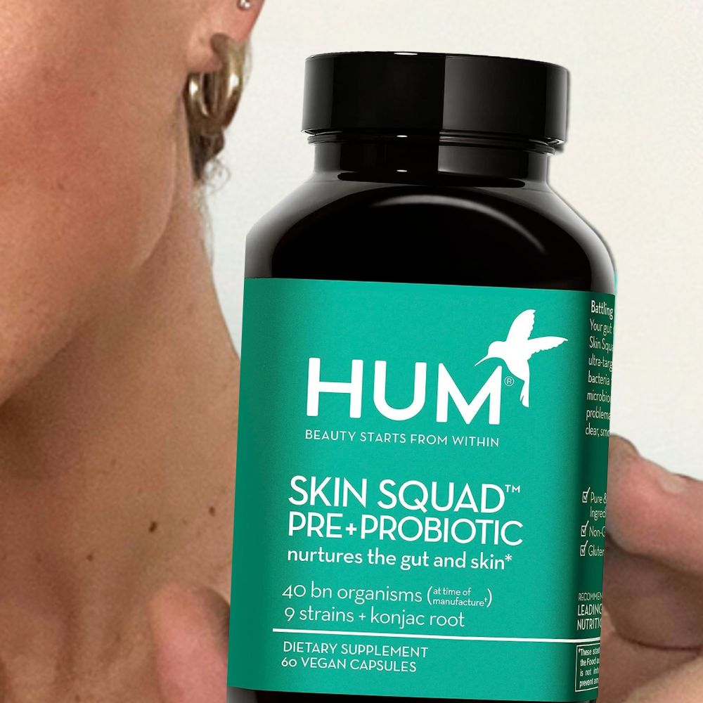 A woman holding a bottle of Hum Skin Squad Pre Probiotic Clear Skin Supplement