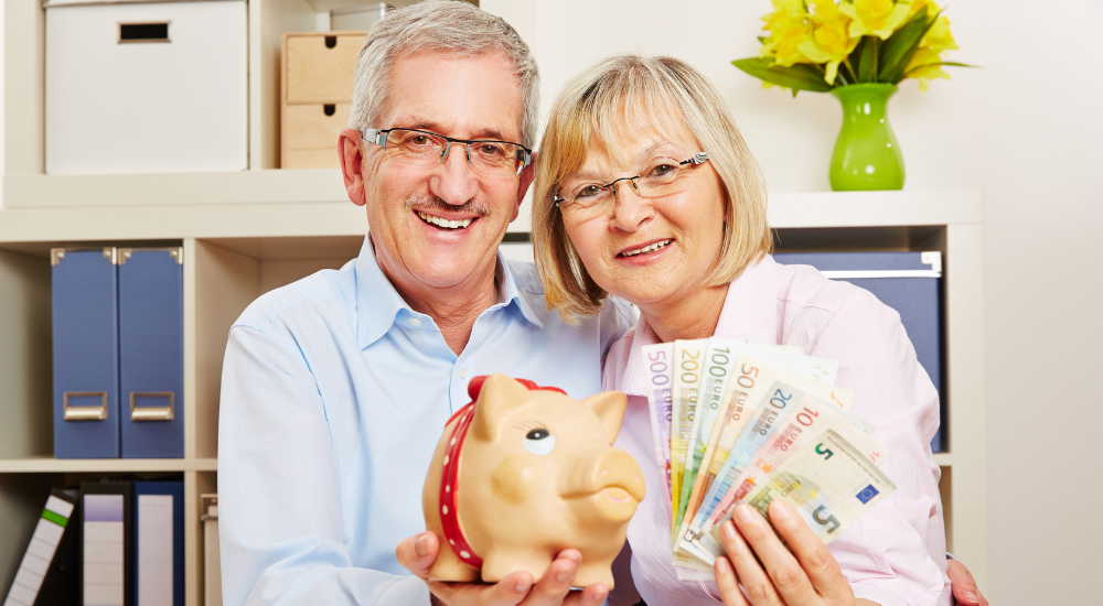 A happy couple showing money and a piggy bank