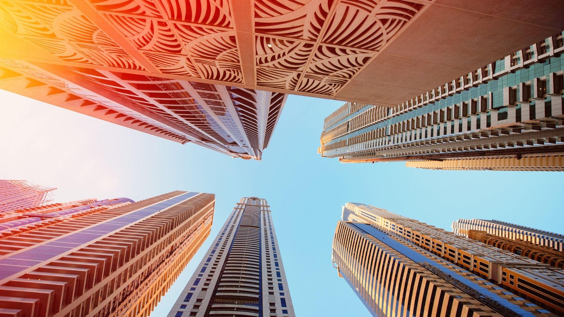 Upward view of modern skyscrapers in Dubai Marina against a clear blue sky, showcasing contemporary urban architecture.