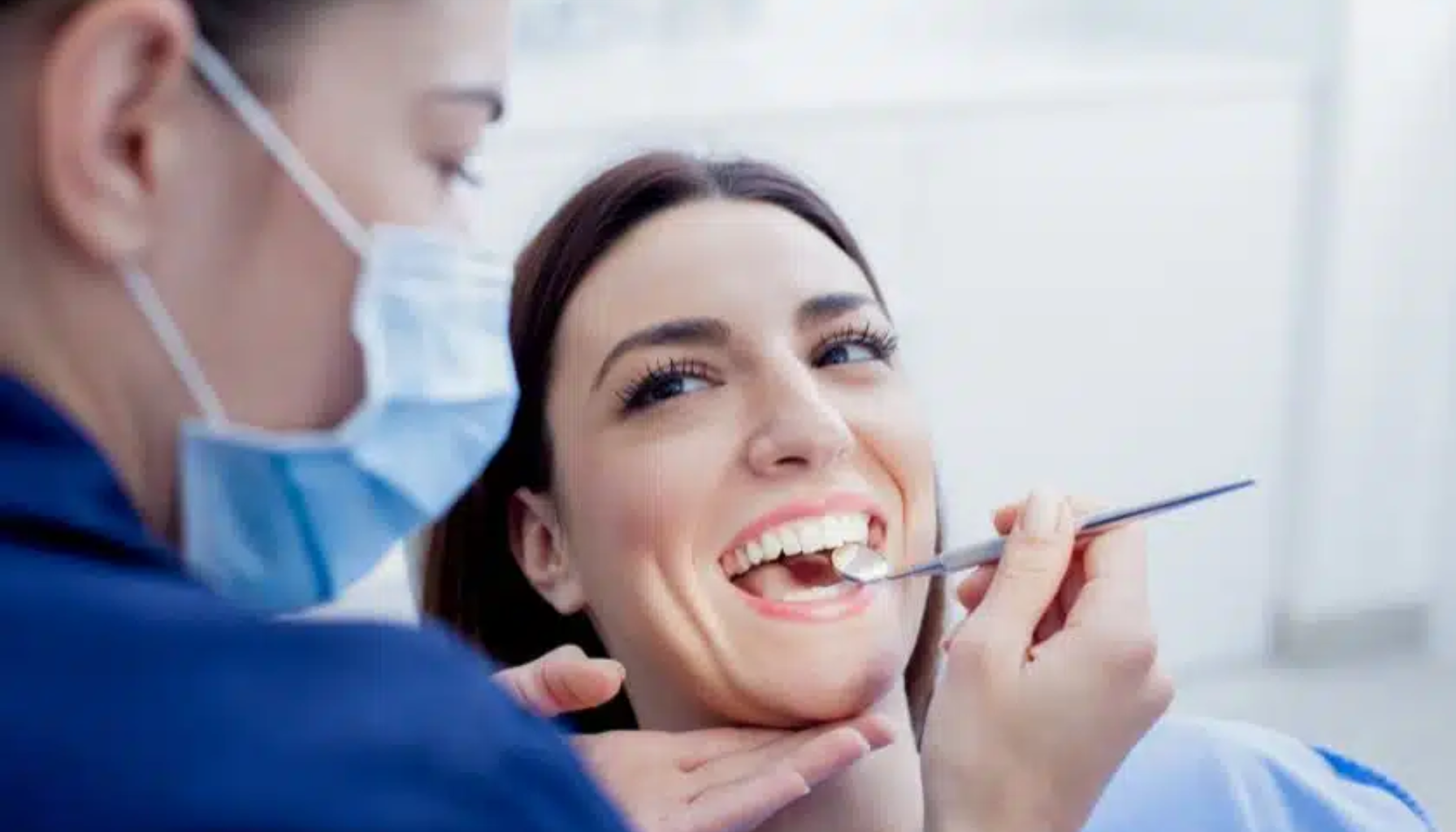 Tannhelsesekretær: Den usynlige helten bak hvert smil 12 Kvinne hos tannlege smiler mens tannlege undersøker tennene hennes med speil og hansker i klinisk miljø hvitt