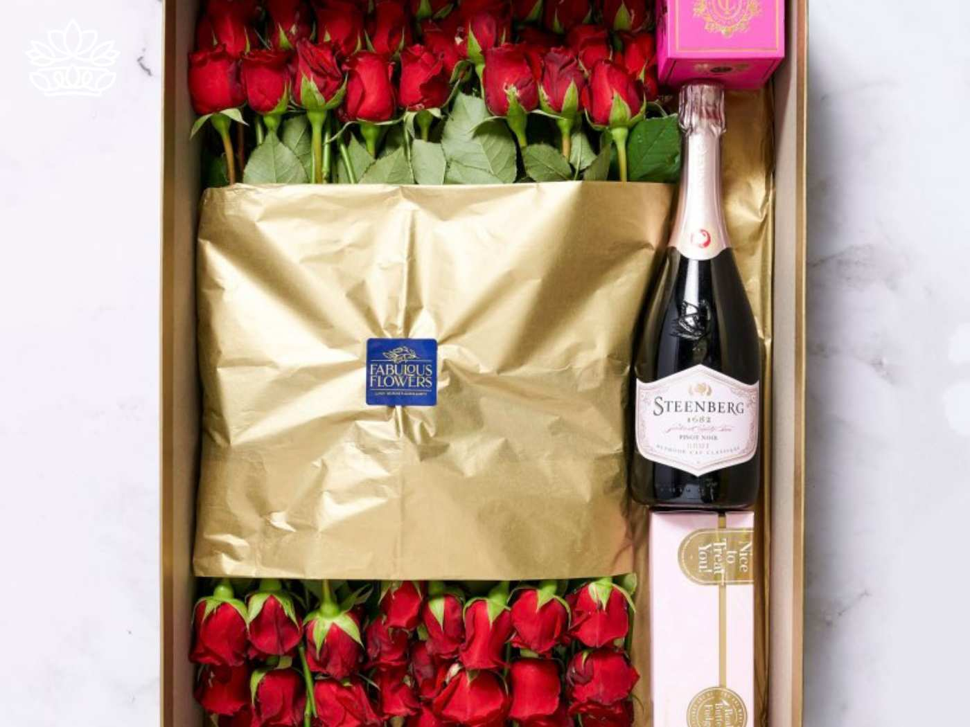 Luxurious gift box with vibrant red roses and a bottle of premium sparkling wine, packaged beautifully alongside a pink box of chocolates, perfect for celebrating momentous achievements. Graduation. Delivered with Heart. Fabulous Flowers and Gifts.