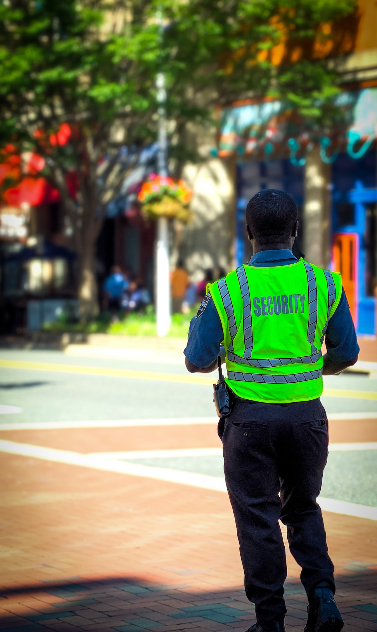 (Source: unsplash.com/@thenewmalcolm) Security Guard in a neon green vest watches over a 4way intersection