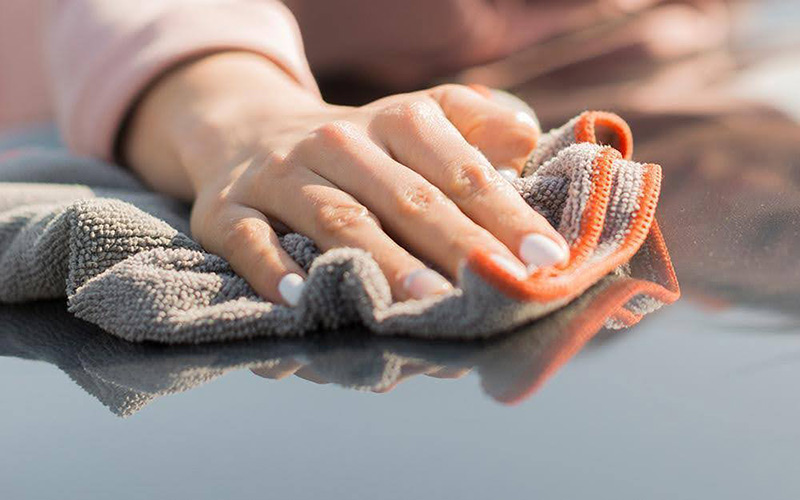 Women Cleaning Car Roof with Microfiber Towel