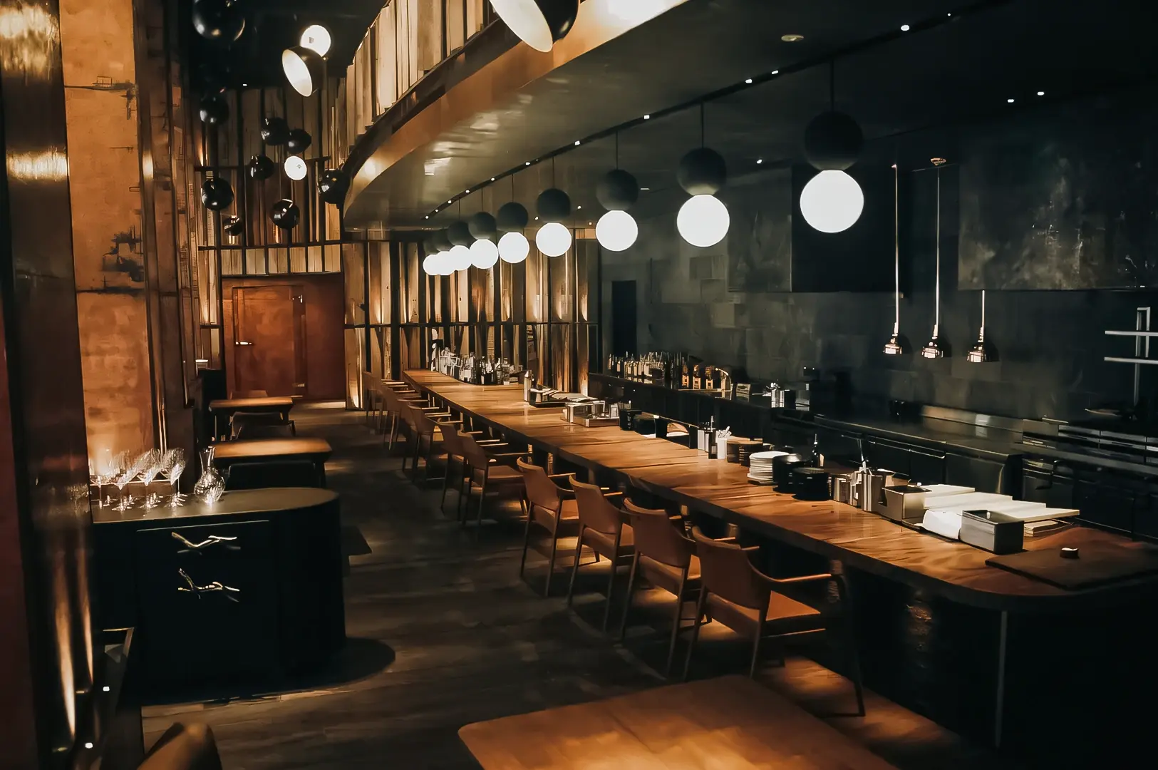 Eye‑level wide shot of a modern chef’s counter dining space, featuring a long wooden bar, pendant globe lights, open kitchen workspace, and minimalist restaurant design.