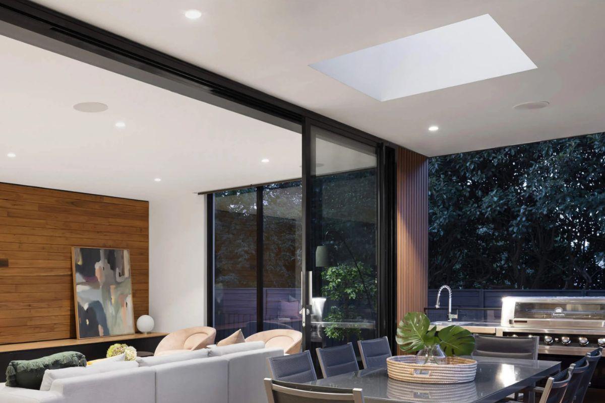 Open-concept dining area with recessed lighting, skylight and large glass doors to an outdoor kitchen