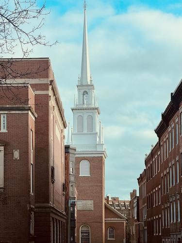 A church steeple in Boston above cobblestone streets on a quick trip for art galleries 