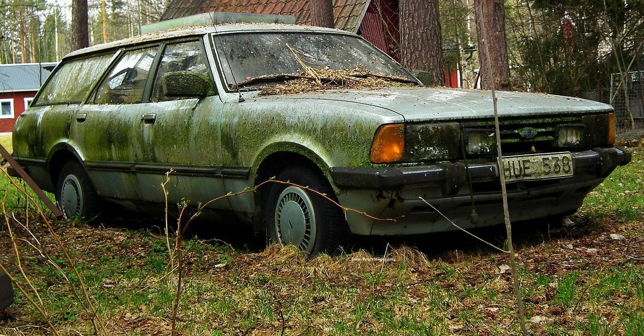 A person assessing the value of a junk car