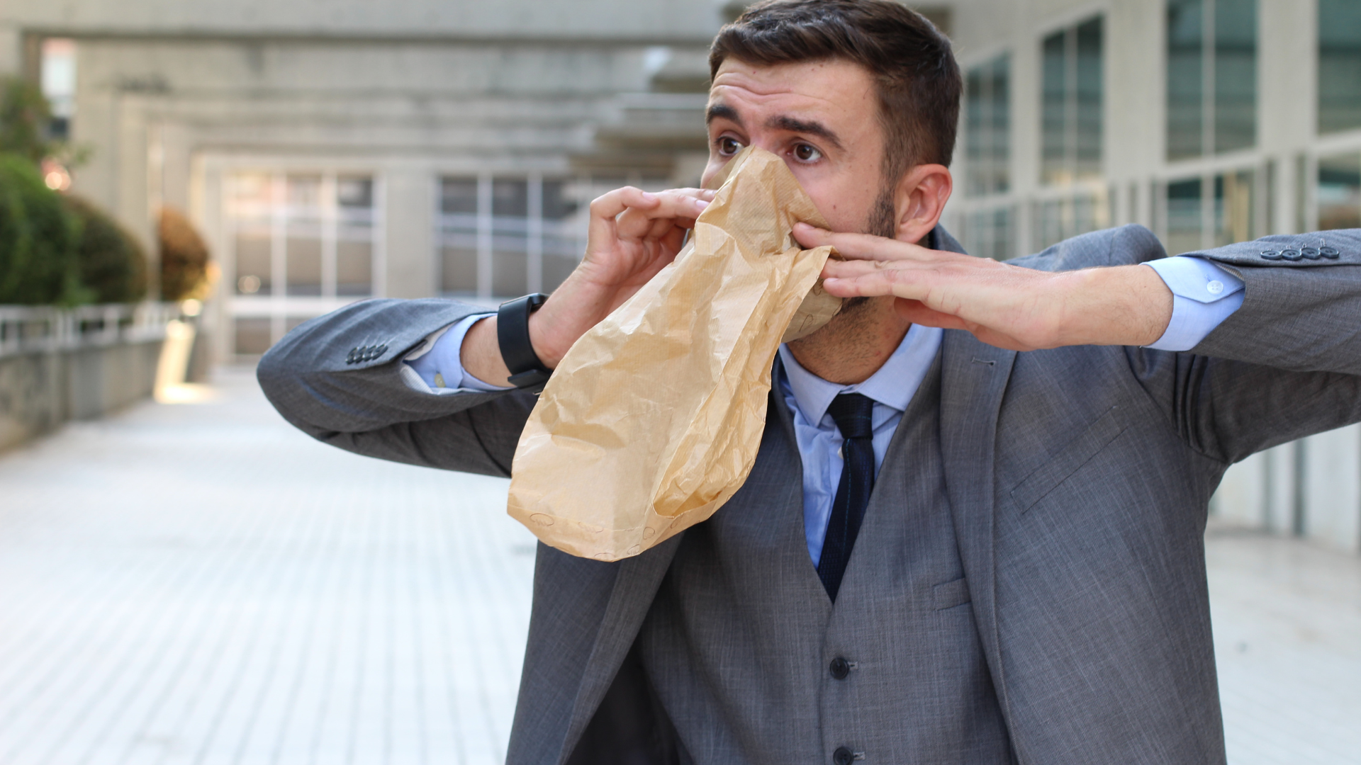 man taking deep breaths in a paper bag