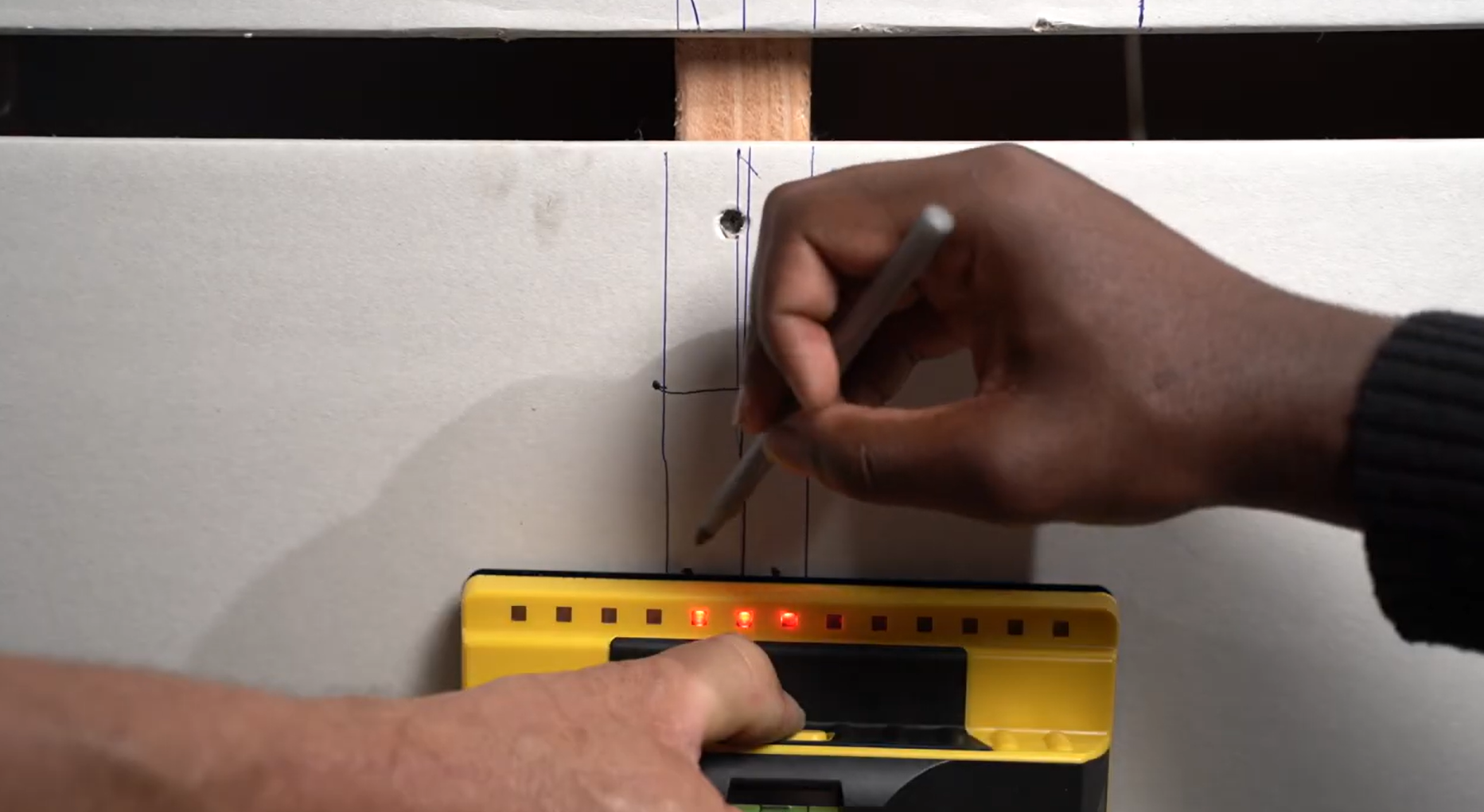 marking the drywall with the area where the wood stud was detected