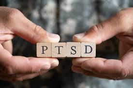 Hands holding wooden blocks spelling out "PTSD."