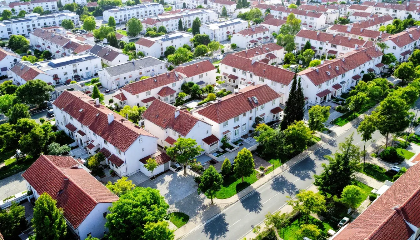 Uma vista aérea de um conjunto habitacional mostra casas organizadas em fileiras, evidenciando a estrutura planejada da construção civil em uma região metropolitana. Essa imagem pode representar oportunidades de financiamento imobiliário e a aquisição de imóveis, refletindo o sonho da casa própria.