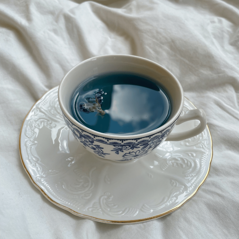 A picture of a cup of blue lotus tea with a blue lotus flower